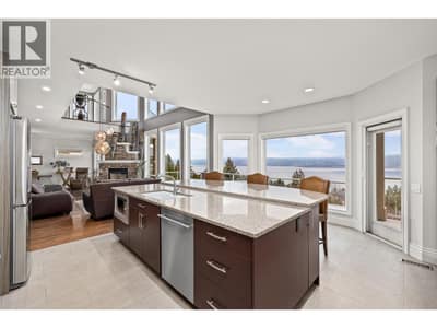 Bright kitchen space with stainless steel appliances through out, an oversized kitchen island and picturesque lake views