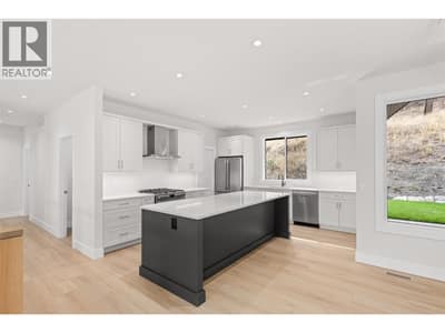 Kitchen | Upper Level - With two-tone Shaker cabinetry, Silestone quartz countertops, designer tile, under-cabinet lighting & Frigidaire Professional appliances including a gas range