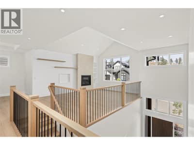 Living Room | Upper Level - soaring vaulted & open-to-below ceilings, wide-plank flooring, custom white-oak details and a Napoleon fireplace with full-height plaster surround