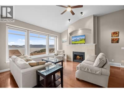 Living room with gas fireplace, vaulted ceilings, large windows to showcase the lake and mountain views