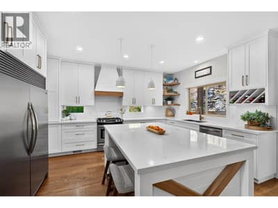Bright, beautifully renovated kitchen with large island, quartz countertops, side by side fridge and custom cabinetry.