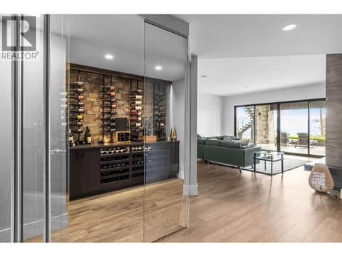 Custom glass-enclosed wine cellar with stone accent wall and engineered hardwood flooring in a luxury Kelowna home. at 162 Skyland Drive, Wilden, Kelowna
