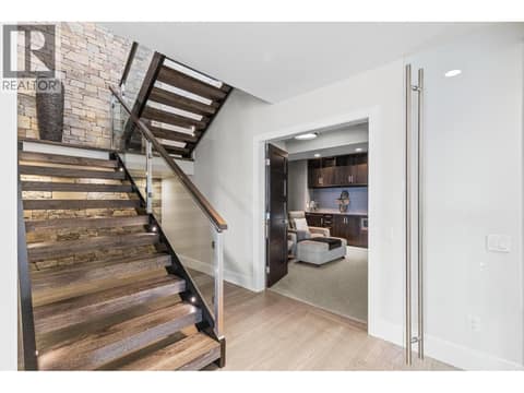 Custom open riser stairs, featuring cozy four-zone radiant in-floor heating, engineered hardwood floors, theatre, wine room, and direct walkout access to the saltwater pool deck. at 162 Skyland Drive, Wilden, Kelowna