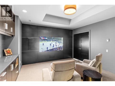 Insulated home theater room with acoustic wall panels, a wall-mounted TV perfect for watching the game, comfortable recliner seating, and built-in media cabinetry. at 162 Skyland Drive, Wilden, Kelowna