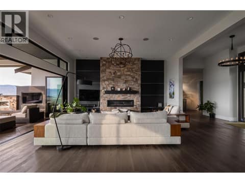 Sophisticated open-concept living. Features soaring wood-accent panels, a custom gas fireplace, and massive eclipse doors, framing panoramic valley and city views. at 162 Skyland Drive, Wilden, Kelowna