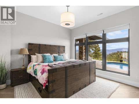 Spacious lower-level bedroom at 162 Skyland Drive, featuring cozy four-zone radiant in-floor heating, engineered hardwood floors, and walkout access to the saltwater pool deck. at 162 Skyland Drive, Wilden, Kelowna