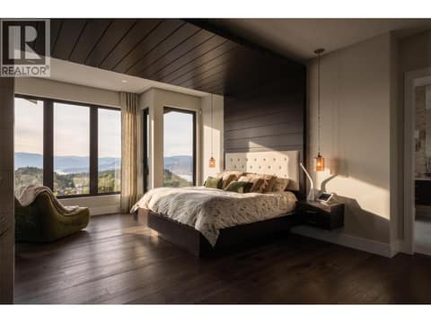The ultimate primary retreat. Sprawling main-floor sanctuary featuring deep wood ceiling accents, warm hardwood floors, and large windows looking out to protected, non-buildable nature below. at 162 Skyland Drive, Wilden, Kelowna