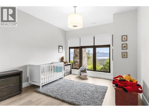 Versatile lower-level bedroom featuring a generous layout, ample closet space, and direct line of sight out to the protected nature setting below the property. at 162 Skyland Drive, Wilden, Kelowna