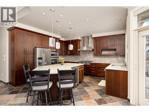 Large gourmet kitchen with 6-burner gas range, wall oven, wine fridge, undermount lighting and kitchen island with seating for 5. at 10726 Nighthawk Road Unit# 60, Lake Country North West