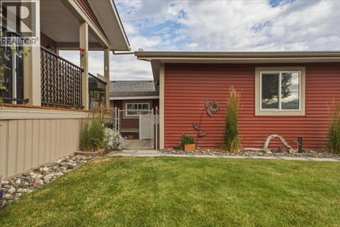 Front yard with gate to side yard (house on left, garage on right) at 12560 Westside Road Unit# 51, Swan Lake West, Vernon