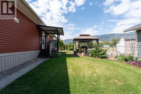 View through the gate to the ""back door"" and side yard. at 12560 Westside Road Unit# 51, Swan Lake West, Vernon