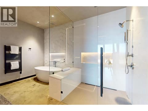 Lower level primary ensuite with glass enclosed shower and tub at 4275 Todd Road, South East Kelowna