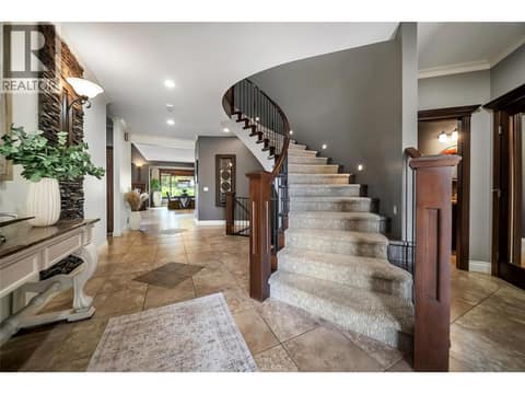 A sweeping curved staircase anchors the entryway. Soaring ceilings and abundant natural light create an unforgettable first impression. at 336 Quilchena Drive, Kettle Valley, Kelowna