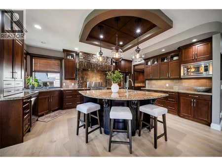The gourmet kitchen features an oversized island, custom wood cabinetry, and premium finishes throughout. Built for both everyday living and entertaining at 336 Quilchena Drive, Kettle Valley, Kelowna