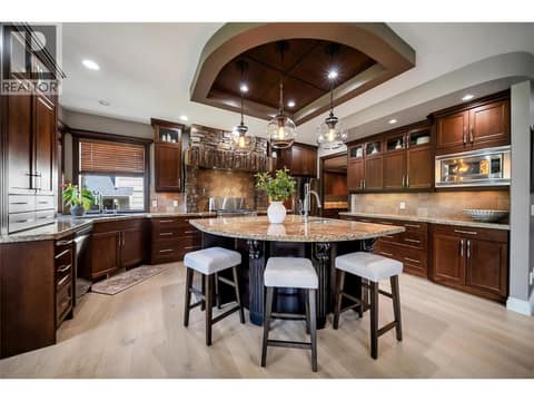 The gourmet kitchen features an oversized island, custom wood cabinetry, and premium finishes throughout. Built for both everyday living and entertaining at 336 Quilchena Drive, Kettle Valley, Kelowna