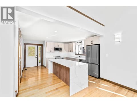 Completely updated kitchen with stainless steel appliances, quartz countertops, and waterfall edge island at 17936 Angus Road, Lake Country North West