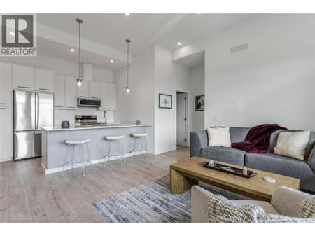 Enjoy the open-concept living room and kitchen with loads of natural light at 1220 Pacific Avenue Unit# 507, Springfield/Spall, Kelowna