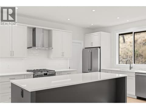 Kitchen | Upper Level - With two-tone Shaker cabinetry, Silestone quartz countertops, designer tile, under-cabinet lighting & Frigidaire Professional appliances including a gas range at 1448 Whistling Pine Place, Wilden, Kelowna