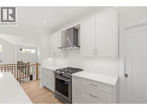 Kitchen | Upper Level - With two-tone Shaker cabinetry, Silestone quartz countertops, designer tile, under-cabinet lighting & Frigidaire Professional appliances including a gas range at 1448 Whistling Pine Place, Wilden, Kelowna