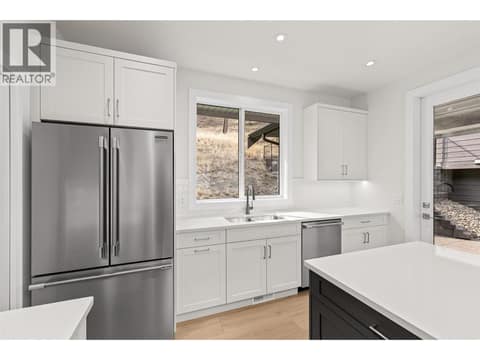 Kitchen | Upper Level - With two-tone Shaker cabinetry, Silestone quartz countertops, designer tile, under-cabinet lighting & Frigidaire Professional appliances including a gas range at 1448 Whistling Pine Place, Wilden, Kelowna