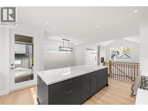 Kitchen | Upper Level - With stainless steel appliances, hard surface countertops, pantry & oversized kitchen island at 1448 Whistling Pine Place, Wilden, Kelowna
