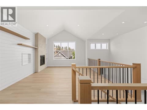 Living Room | Upper Level - soaring vaulted & open-to-below ceilings, wide-plank flooring, custom white-oak details and a Napoleon fireplace with full-height plaster surround at 1448 Whistling Pine Place, Wilden, Kelowna