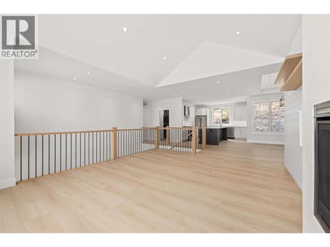 Living Room | Upper Level - soaring vaulted & open-to-below ceilings, wide-plank flooring, custom white-oak details and a Napoleon fireplace with full-height plaster surround at 1448 Whistling Pine Place, Wilden, Kelowna