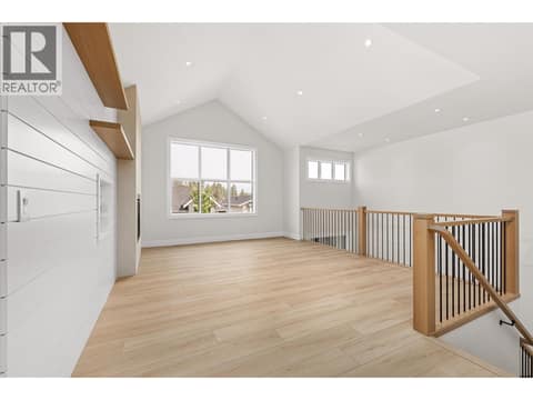 Living Room | Upper Level - soaring vaulted & open-to-below ceilings, wide-plank flooring, custom white-oak details and a Napoleon fireplace with full-height plaster surround at 1448 Whistling Pine Place, Wilden, Kelowna