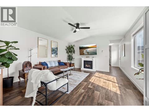 Large windows fill the living room with natural light, while the fireplace adds warmth and character. TV imagery and fireplace flame have been digitally enhanced. at 9020 Jim Bailey Road Unit# 174, Lake Country East / Oyama, Kelowna