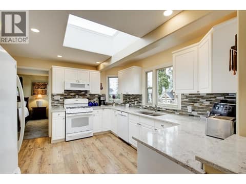 Functional and bright  U-shaped kitchen with modern appliances and partial lake view from kitchen window at 391 Braeloch Road, Upper Mission, Kelowna