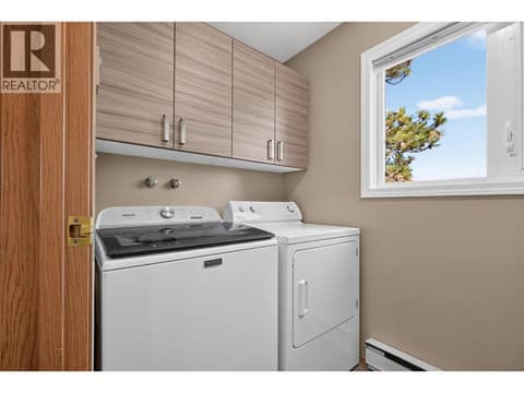 Convenient main-floor laundry with built-in cabinetry for added storage at 3040 Seclusion Bay Road, Westbank Centre, West Kelowna