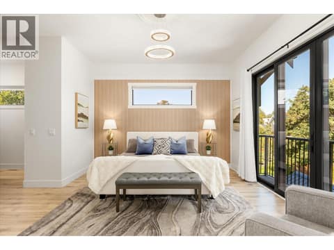 Primary bedroom features a Juliette balcony that overlooks the backyard area at 2053 Long Street, Kelowna South
