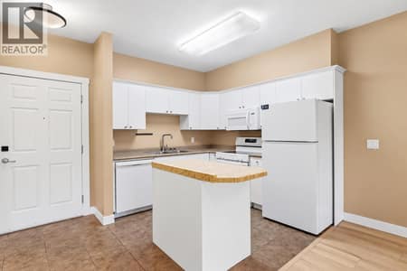 Bright corner kitchen with white cabinetry & laminate countertops at 1125 Bernard Avenue Unit# 302, Kelowna North