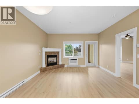 Open-concept living space featuring a corner fireplace with tile surround and mantle at 1125 Bernard Avenue Unit# 302, Kelowna North