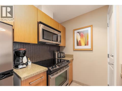 Kitchen cooking area with stainless-steel appliances and tiled backsplash. at 15 PARK Place Unit# 209, Osoyoos