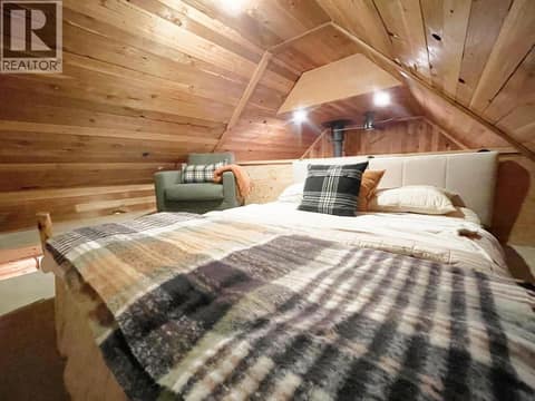 A-frame loft sleeping area with bed and chair at 1166 Apex Mountain Road, Penticton Apex