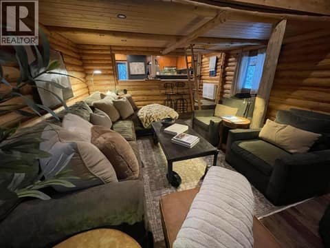 Living room seating area with log walls and wood flooring at 1166 Apex Mountain Road, Penticton Apex