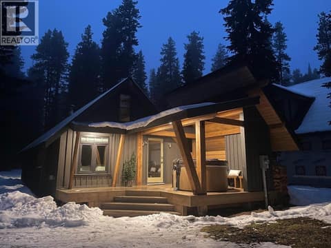 Snow-covered cabin exterior at dusk with illuminated entry at 1166 Apex Mountain Road, Penticton Apex