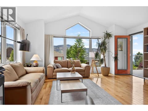 Open concept layout with a cathedral ceiling, stone fireplace with gas stove, and panoramic lake and mountain views. at 183 Magic Drive, Glenmore, Kelowna