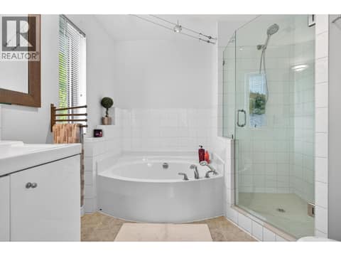 Primary Ensuite featuring a relaxing corner soaker tub and glass enclosed walk in shower at 183 Magic Drive, Glenmore, Kelowna