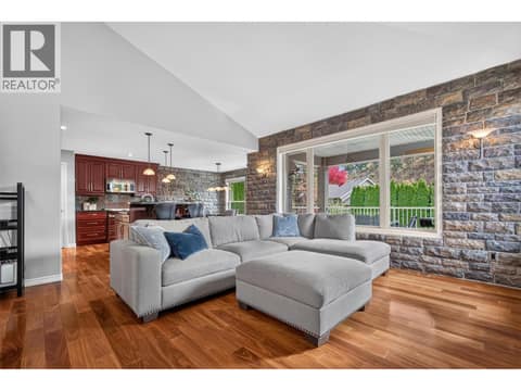 Spacious living room featuring vaulted ceilings, a striking rock feature wall, and an electric fireplace, creating a warm and inviting space to relax or entertain. at 2512 Selkirk Drive, Dilworth Mountain, Kelowna